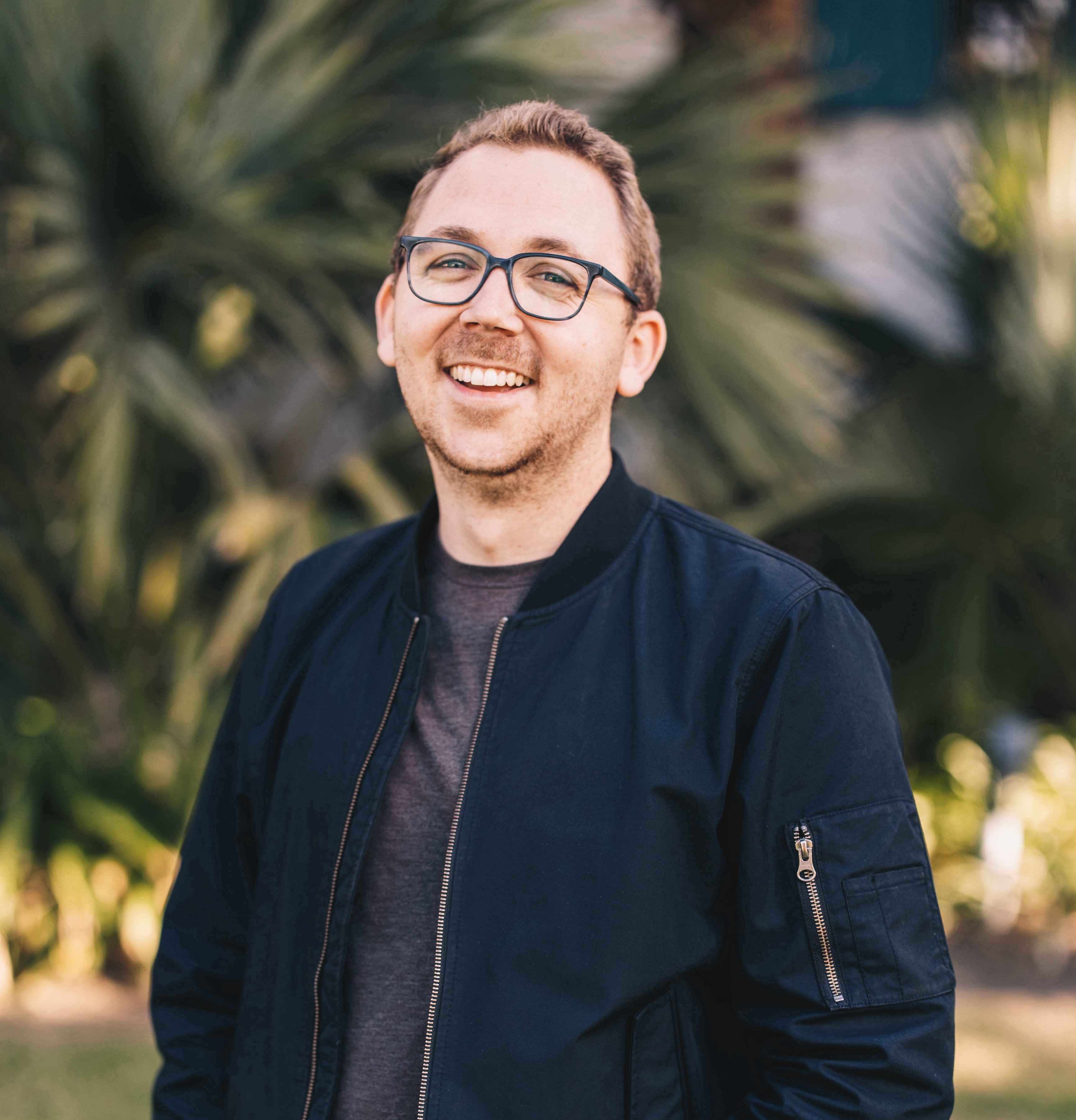 Photo of course instructor. A caucasian, male-presenting person with glasses in a dark jacket